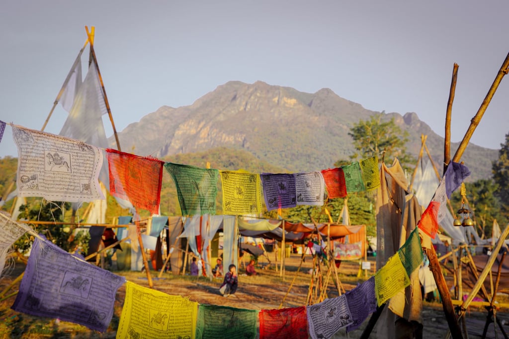 Shambhala campsite decorated with colourful flags, with Doi Chiang Dao in the background, Thailand. Photo: David Frazier