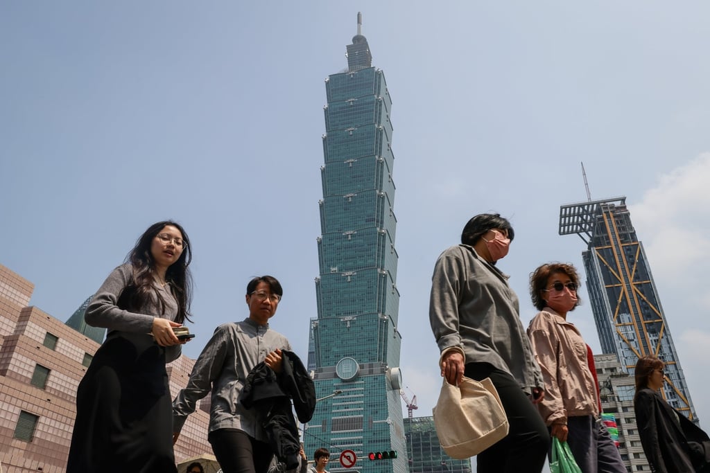 People cross a street under the Taipei 101 skyscraper building in Taiwan, on March 24. Photo: EPA