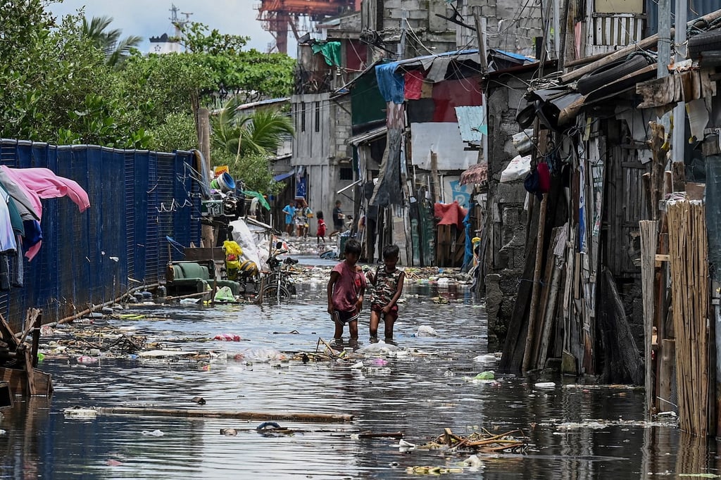 Children walk through a flooded area in Baseco, one of the biggest slums in Manila, the Philippines. Photo: AFP