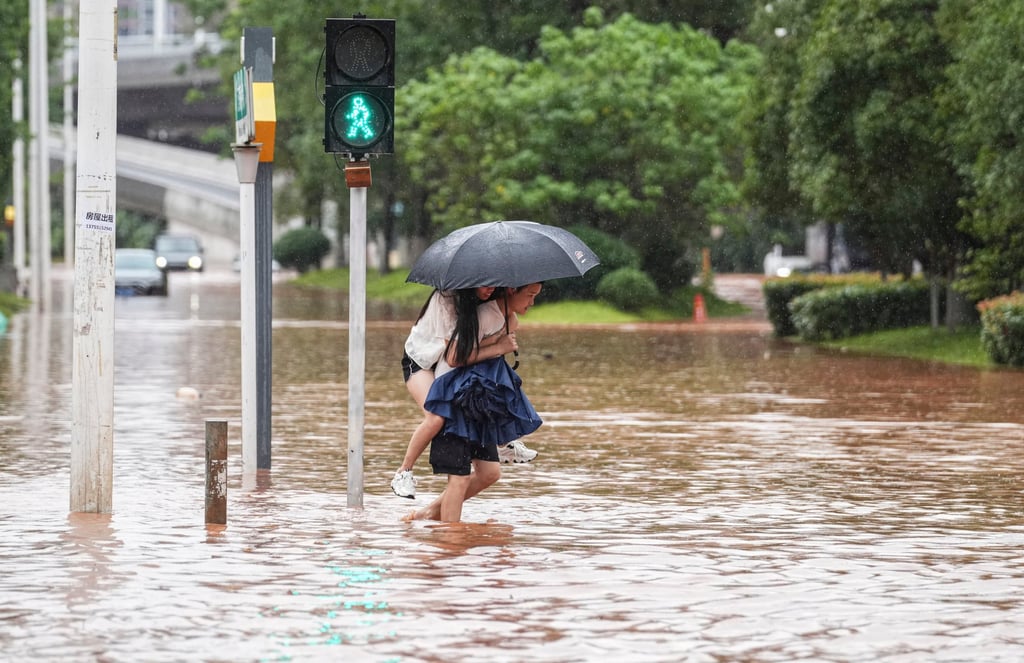 People wade through a flooded street following heavy rains in Changsha, southern China. Photo: AFP