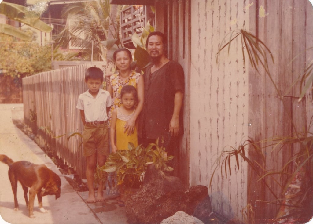 An undated photograph shows Tang Chang with his wife and two children outside their home in Bangkok, Thailand. His pseudo-calligraphy, which is illegible, can be seen painted on the door beside them. Photo: Tang Chang Private Museum