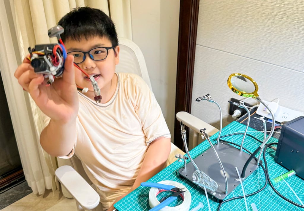 Che Jingang holds an engine part up to the camera as he works on his creation. Photo: Handout