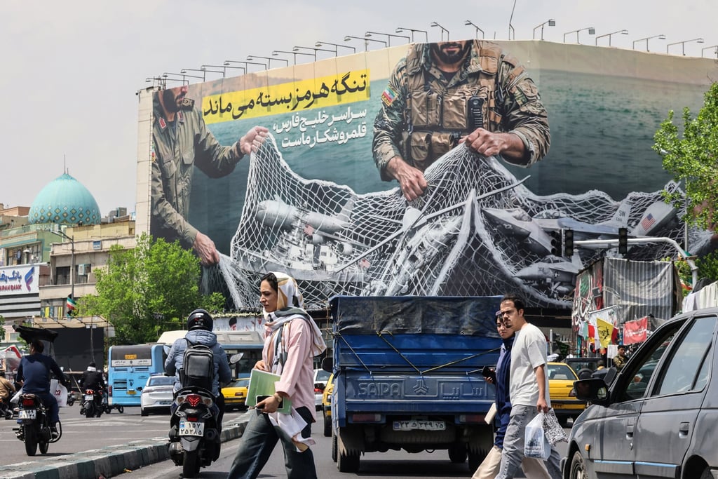 Iranians walk past a giant hoarding reading “The Strait of Hormuz remains closed” in Tehran on Wednesday. Photo: AFP/Getty Images/TNS