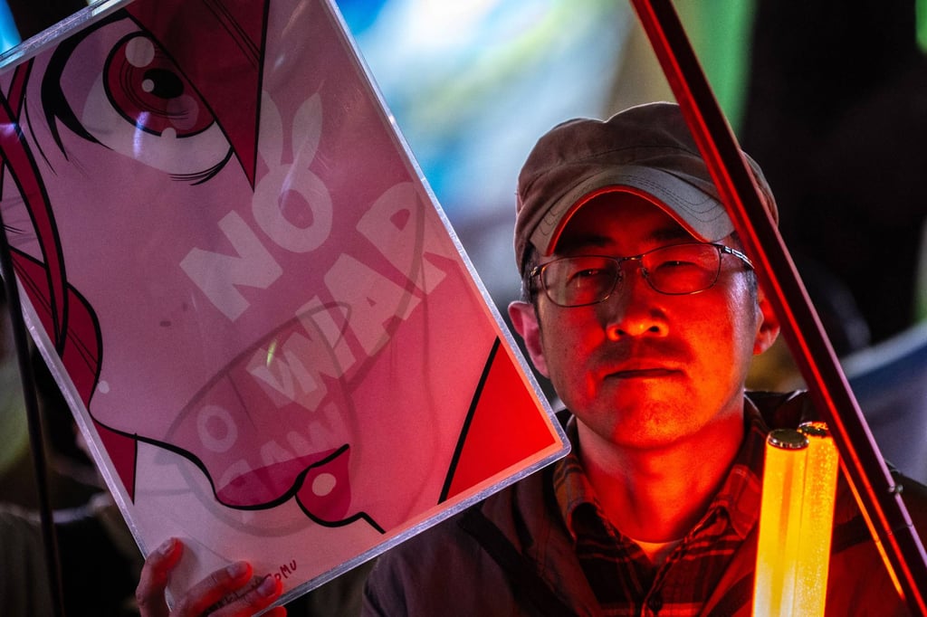 A man holds a placard reading “No War” during a protest against Japan’s lethal arms export rule change, in Tokyo’s Shinjuku district on April 24, 2026. (Photo by Philip FONG / AFP)