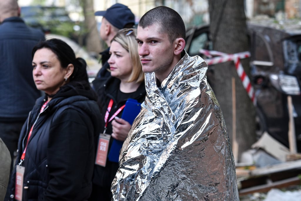 A man covered in a thermal blanket stands in the yard of a residential building damaged by a Russian strike on Dnipro, Ukraine, on Saturday. Photo: AP