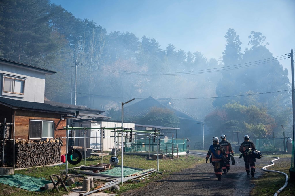 Firefighters carry gear through heavy smoke towards the fire in the town of Otsuchi in Iwate Prefecture on Sunday. Photo: AFP