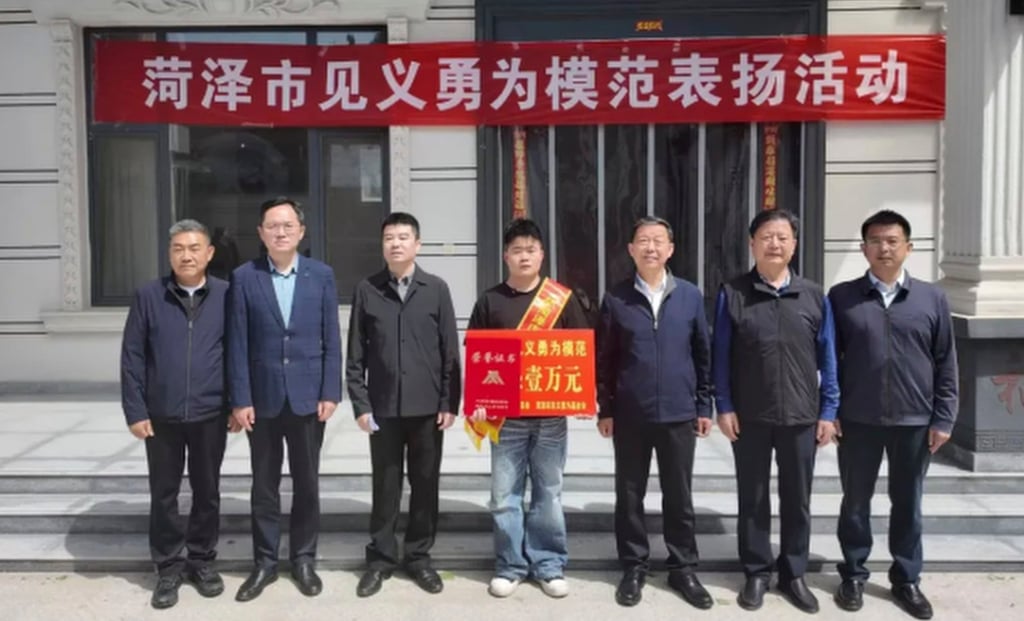 Officials, above, presented Zhang, centre, with a banner and a cash prize for the bravery he showed. Photo: QQ.com