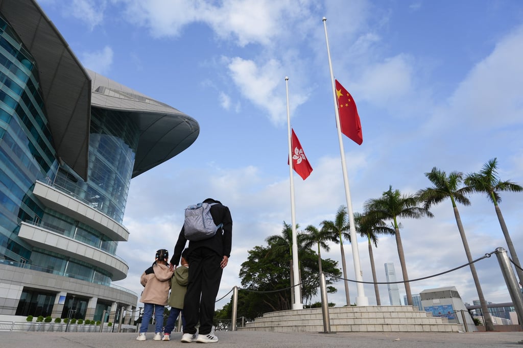 A father and his children stand solemnly at Golden Bauhinia Square in Wan Chai to mourn the fire victims of Wang Fuk Court in Tai Po, last November. Photo: Eugene Lee