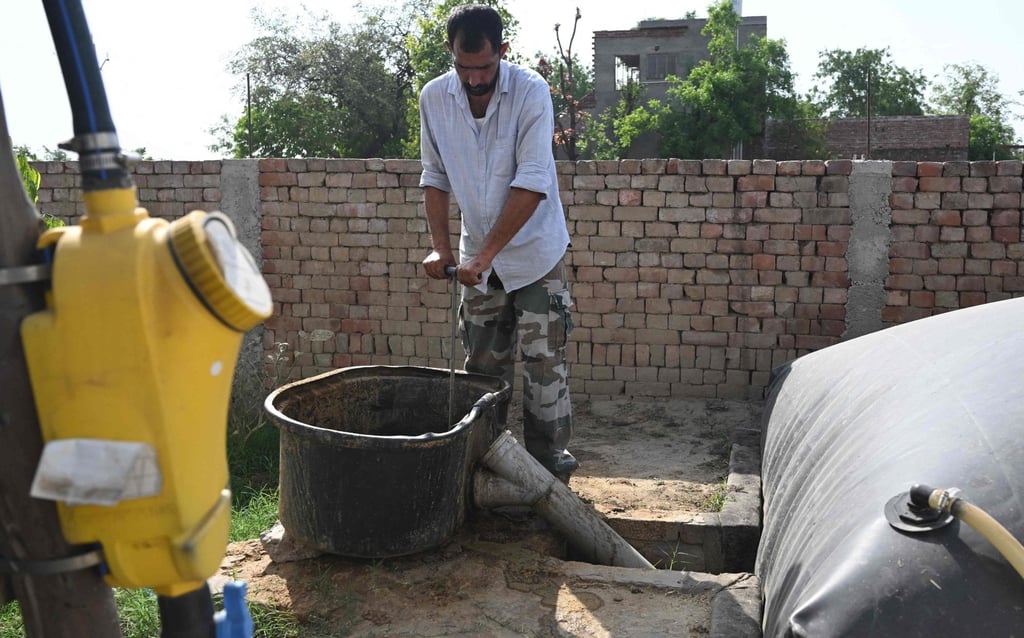 A man pours cow dung into his biogas plant at a village in Uttar Pradesh’s Bulandshahr district. Photo: AFP