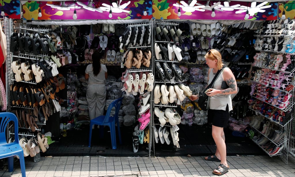 A foreign tourist browses sandals at a roadside shop in Bangkok on April 20. Photo: EPA