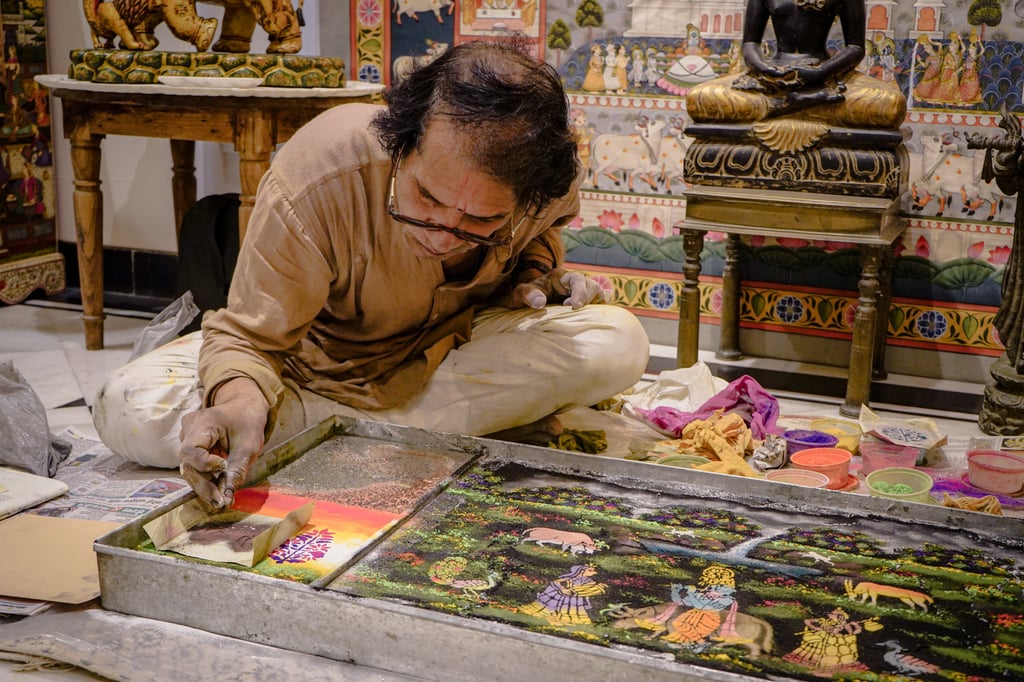 Shri Rajesh Vaishnav creates a Jal Sanjhi work by stencilling pigment on holy water from the River Ganges. Photo: Gavin Yeung
