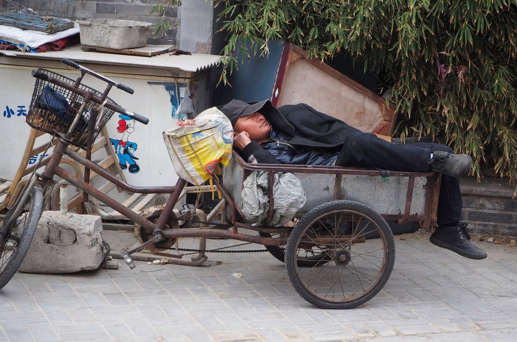 A tired out man sleeping on his tricycle cart in Beijing. Photo: Shutterstock