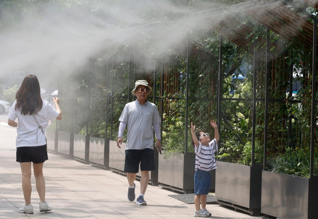 People walk under cooling mists during a heatwave near Seoul City Hall on August 1, 2025. Photo: EPA
