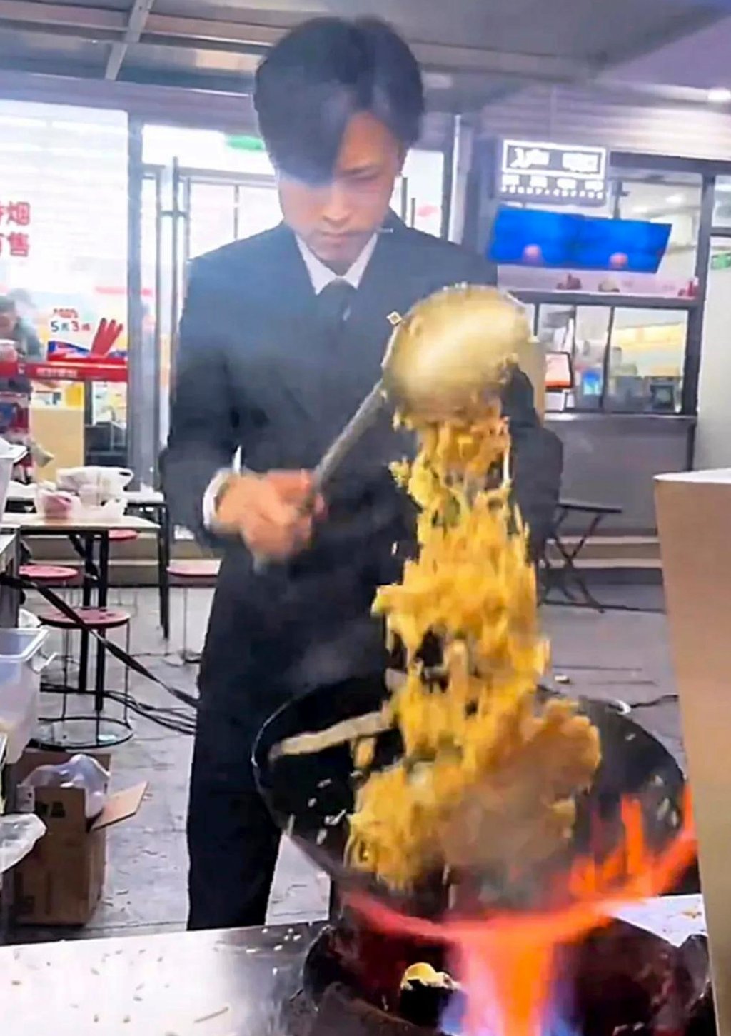 The suited and booted Lu flips his wok in traditional style in the kitchen heat. Photo: Sina