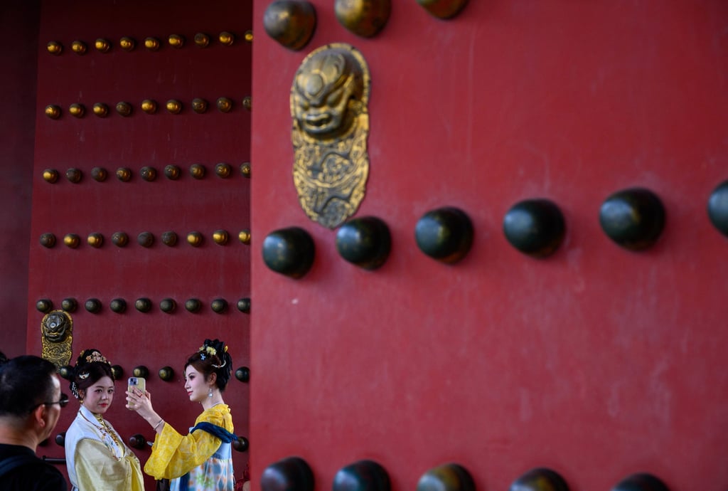 A man looks at two women in traditional attire at the red gates of the Forbidden City in Beijing. Photo: Xinhua A man looks at two women in traditional attire at the red gates of the Forbidden City in Beijing. Photo: Xinhua