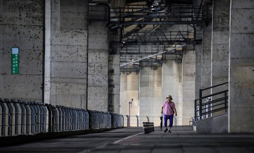 An elderly woman walks on a path under a highway that runs along the Han River in Seoul. Photo: AFP