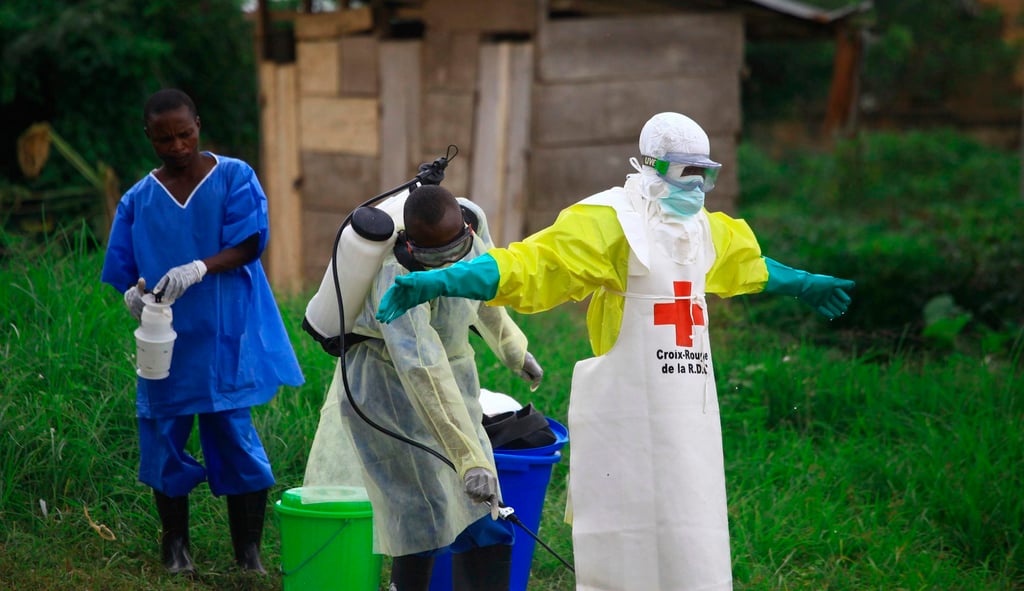 A health worker sprays disinfectant on his colleague after working at an Ebola treatment centre in Beni, eastern Congo, in 2018. Photo: AP