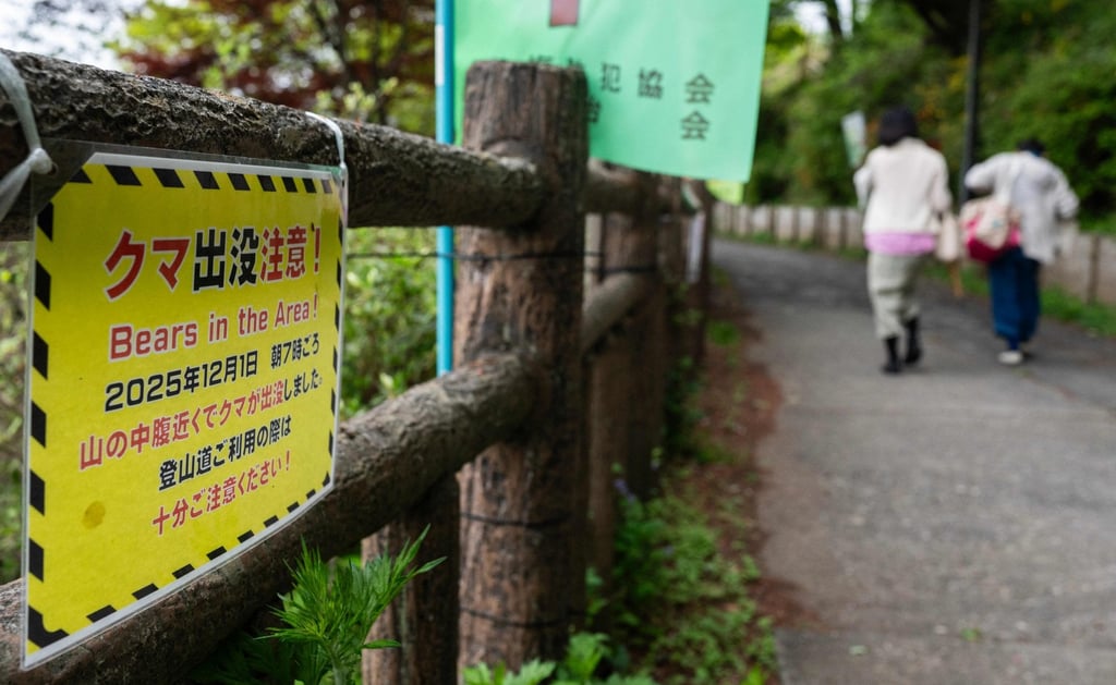 Hikers walk past a sign warning of bears in the area in Ome, Tokyo prefecture, on April 29. Photo: AFP