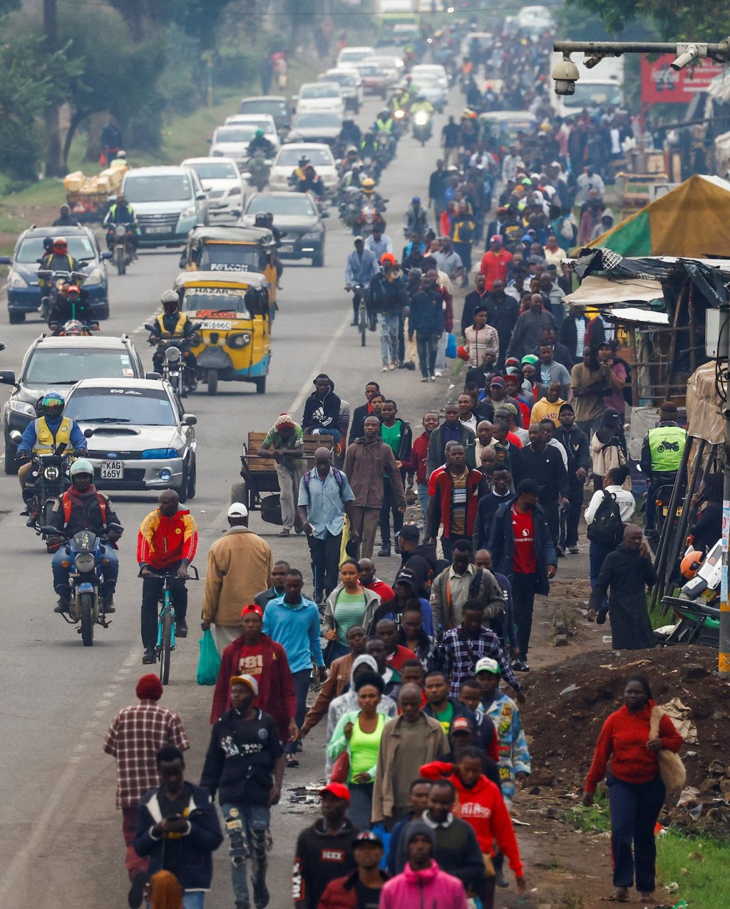 Commuters walk as private motorists drive along a Nairobi road during a public transport strike on Monday. Photo: Reuters