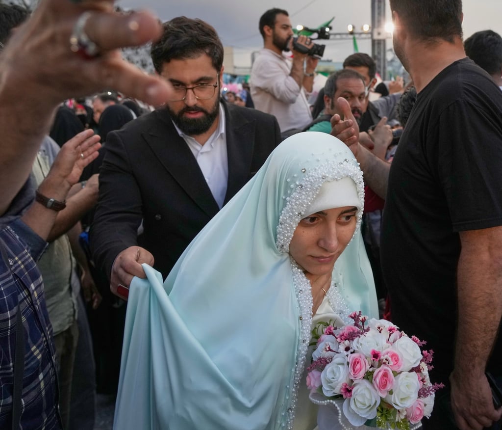A bride and groom walk among attendants during a mass wedding ceremony for participants in the “janfada” pro-government campaign in Tehran on Monday. Photo: AP