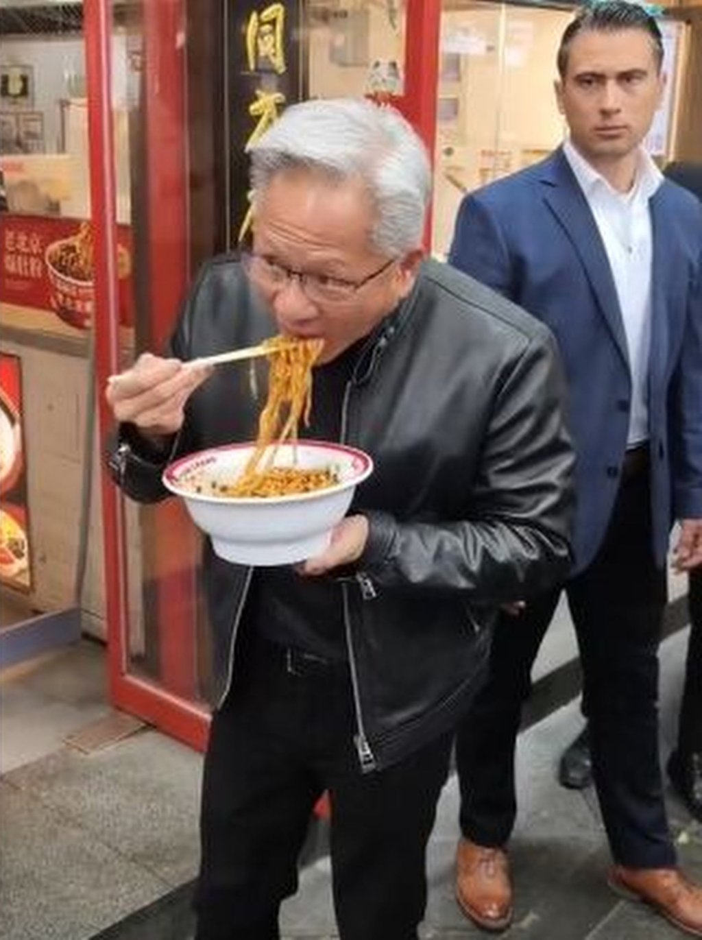 Jensen Huang, above, tucks into a bowl of noodles outside the Beijing shop. Photo: Weibo
