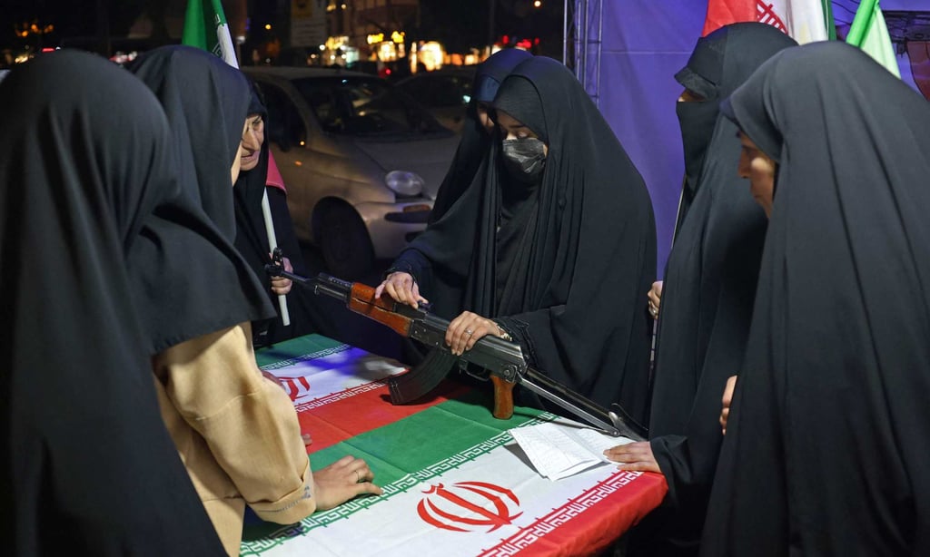 An Iranian military personnel shows women how to use a gun at a booth in Hafte Tir Square in Tehran on Sunday. Photo: AFP