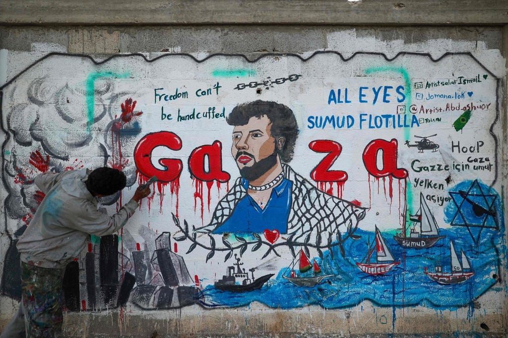 A Palestinian artist paints a mural depicting Israel’s interception of ships taking part in the Global Sumud Flotilla in Nuseirat in the central Gaza Strip on Tuesday. Photo: AFP