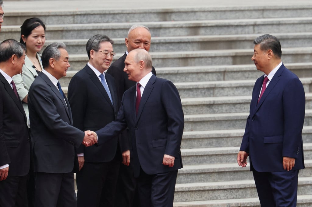 Russian President Vladimir Putin (center) shakes hands with Chinese Foreign Minister Wang Yi during his meeting with President Xi Jinping (right) at the Great Hall of the People in Beijing, May 20. Photo: Reuters