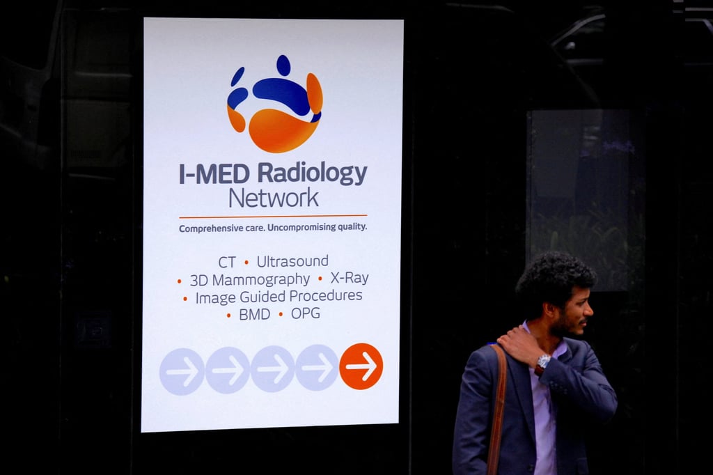 A pedestrian stands next to a banner for Australia’s I-MED Radiology Network in Sydney. Photo: Reuters A pedestrian stands next to a banner for Australia’s I-MED Radiology Network in Sydney. Photo: Reuters