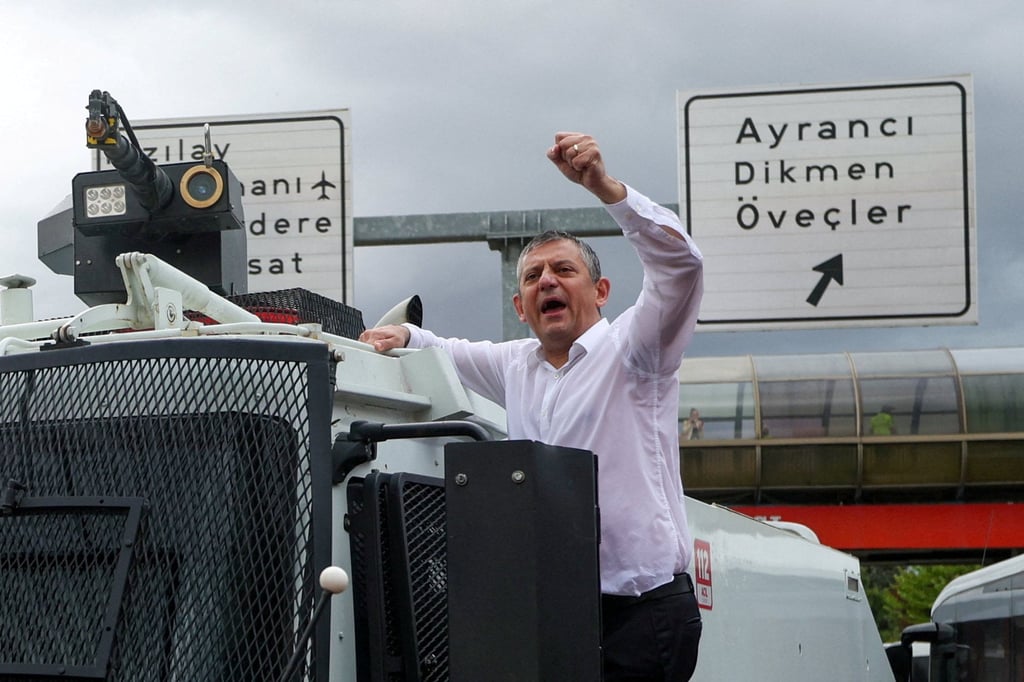 Ousted CHP leader Ozgur Ozel gestures defiantly next to an armoured police vehicle on Sunday. Photo: Reuters