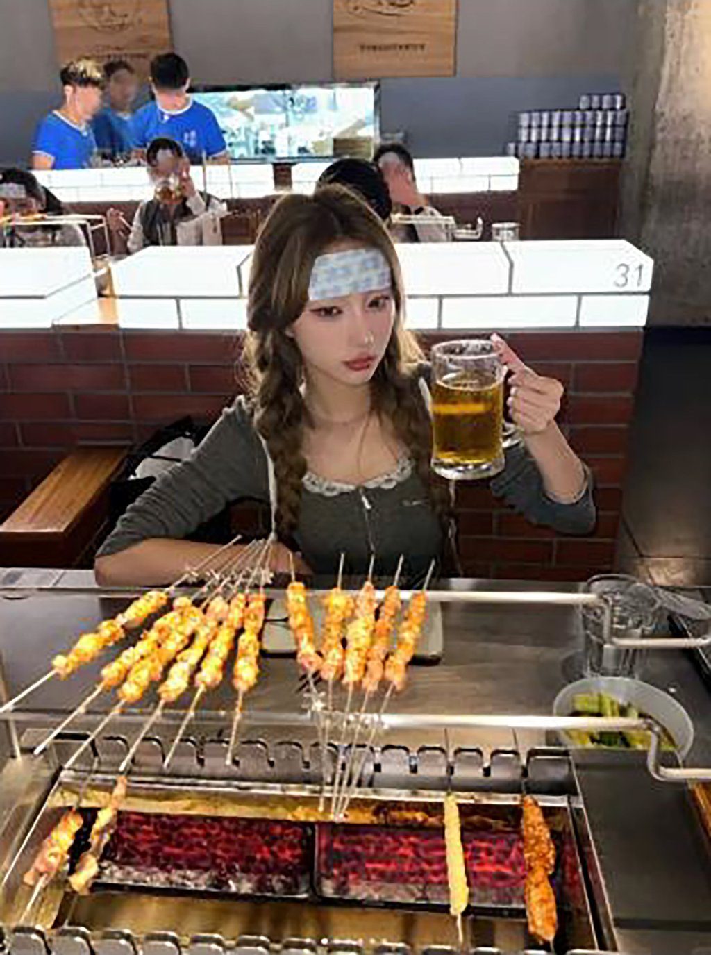 A woman customer, above, enjoys a beer before tucking into some grilled food. Photo: RedNote