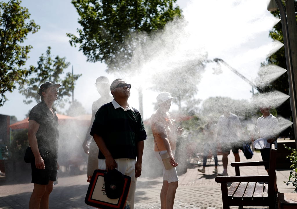 French Open spectators cool down by a water spray station during heatwave in Paris on Monday. Photo: Reuters
