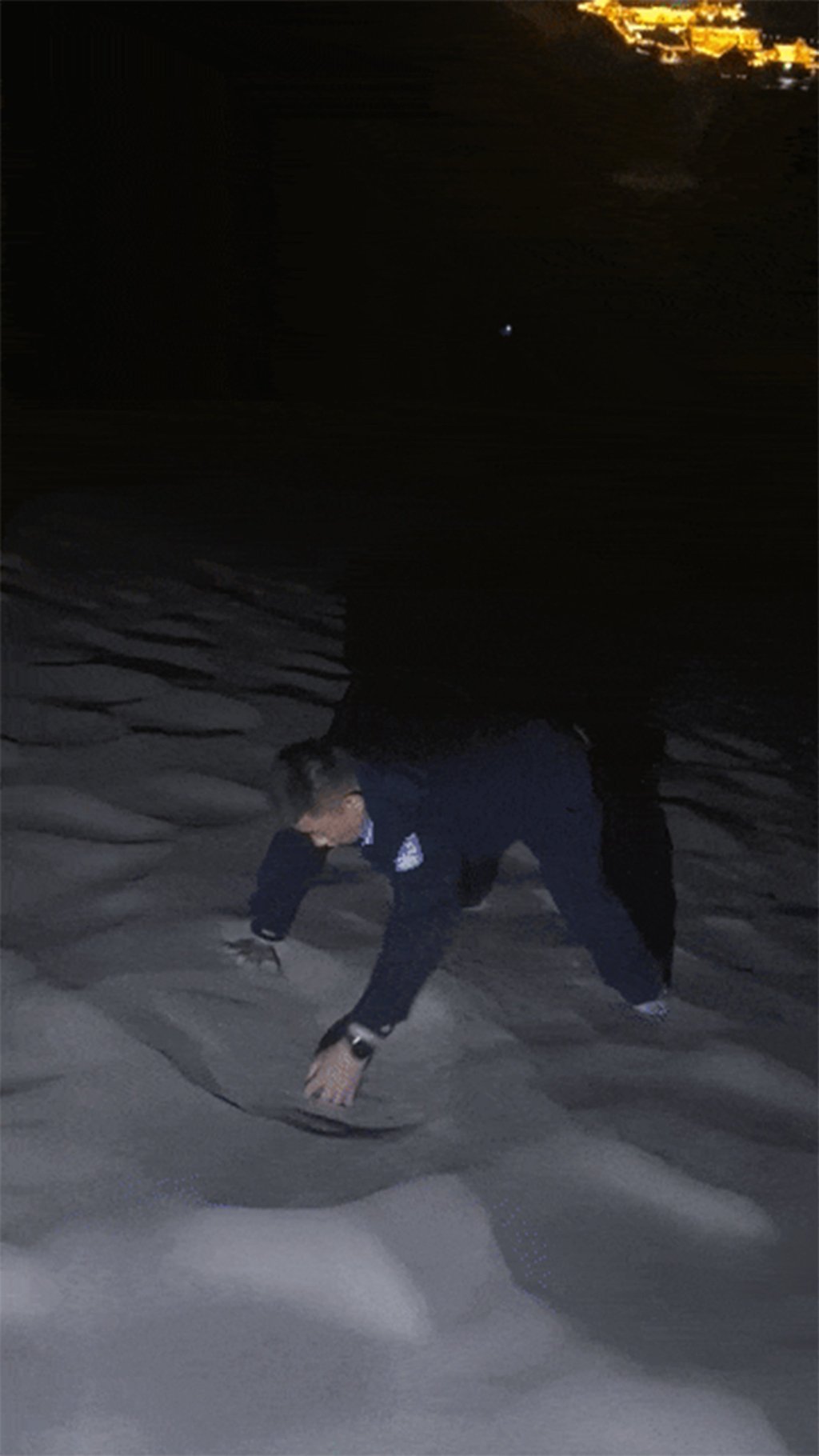 A police officer, above, uses his bare hands to search through the sand in the dark. Photo: weixin