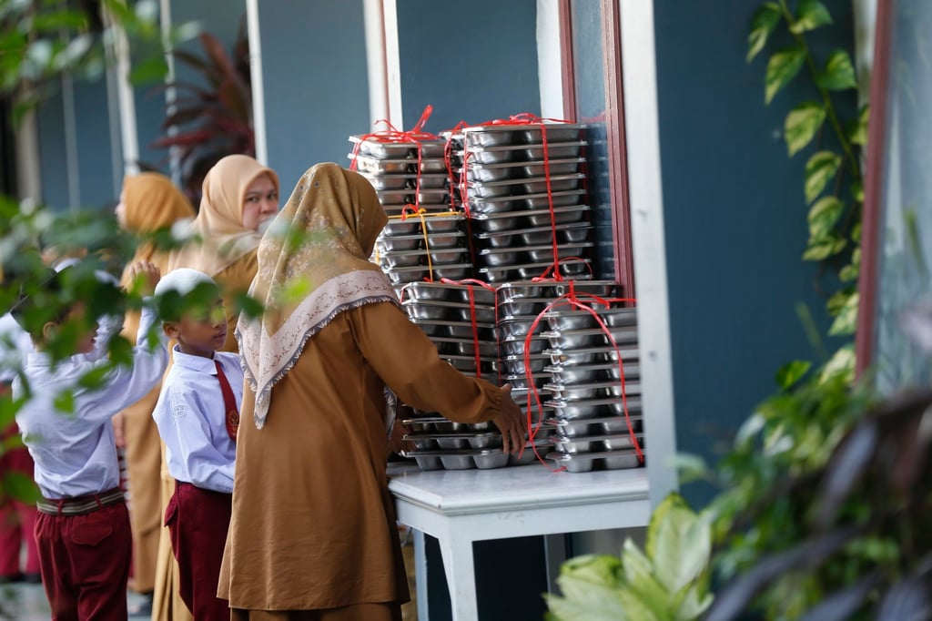 A teacher distributes free meals for students in a school in Banda Aceh, Indonesia last month. Photo: EPA A teacher distributes free meals for students in a school in Banda Aceh, Indonesia last month. Photo: EPA