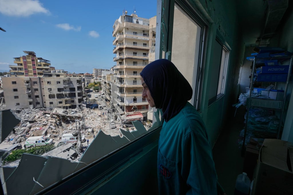 A nurse looks through a broken window of the Jabal Amel Hospital on Tuesday at the damaged building that was hit by an Israeli strike in Tyre, Lebanon. Photo: AP