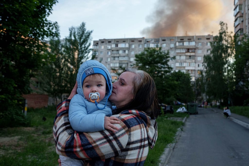 A woman carries a baby near a house damaged after a Russian strike in Kyiv, Ukraine, on Tuesday. Photo: AP