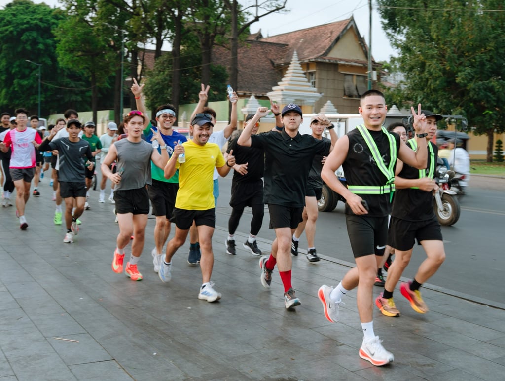 Ngy Sovanratany (second right) flashes a victory sign as he leads members of the Kak Runner Club past the Royal Palace of Cambodia in Phnom Penh. Photo: Skor and Kak Runner Club Ngy Sovanratany (second right) flashes a victory sign as he leads members of the Kak Runner Club past the Royal Palace of Cambodia in Phnom Penh. Photo: Skor and Kak Runner Club