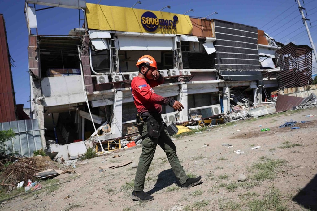 A rescuer walks past a damaged building on Tuesday following the earthquake in General Santos, the Philippines. Photo: AP A rescuer walks past a damaged building on Tuesday following the earthquake in General Santos, the Philippines. Photo: AP