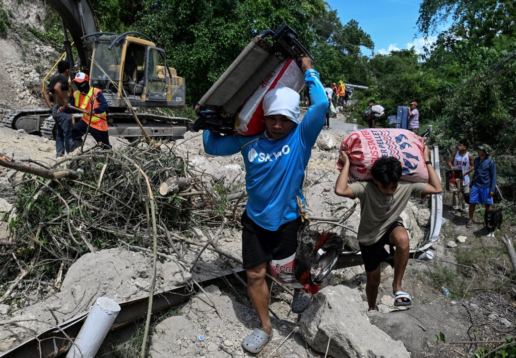 People living on the mountainside carry their belongings as they evacuate after a landslide following the magnitude 7.8 quake in Barangay Kapatan, Glan on Wednesday. Photo: Reuters People living on the mountainside carry their belongings as they evacuate after a landslide following the magnitude 7.8 quake in Barangay Kapatan, Glan on Wednesday. Photo: Reuters