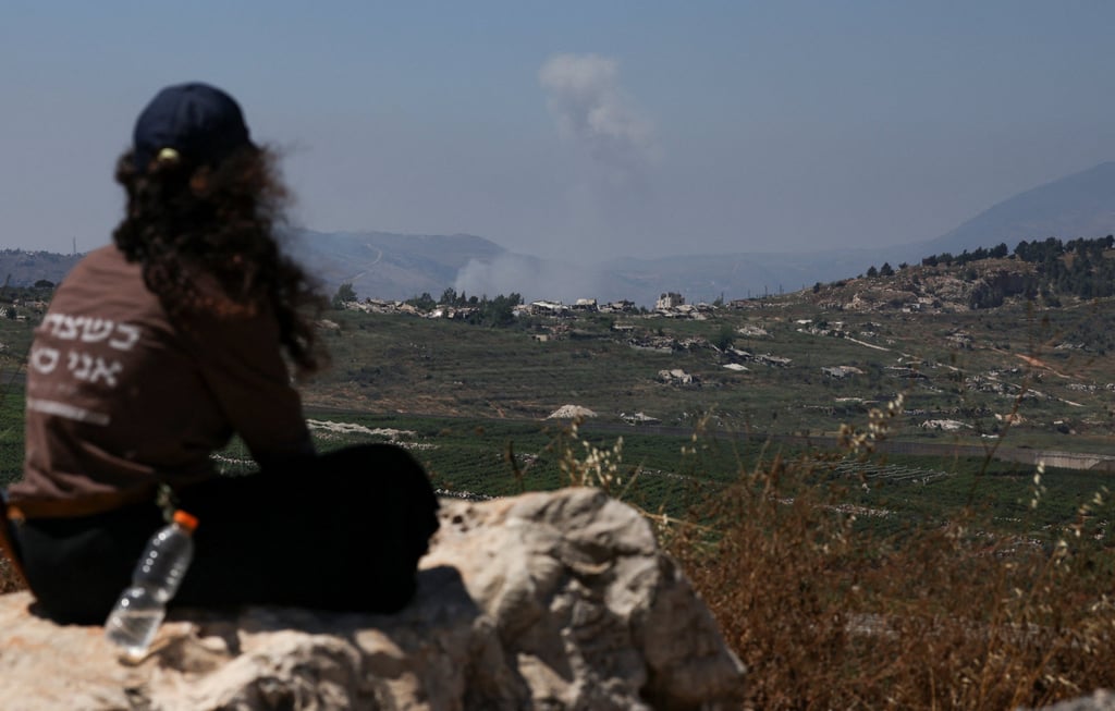 A woman looks at smoke rising in southern Lebanon from the Israeli side of the border on Wednesday. Photo: Reuters