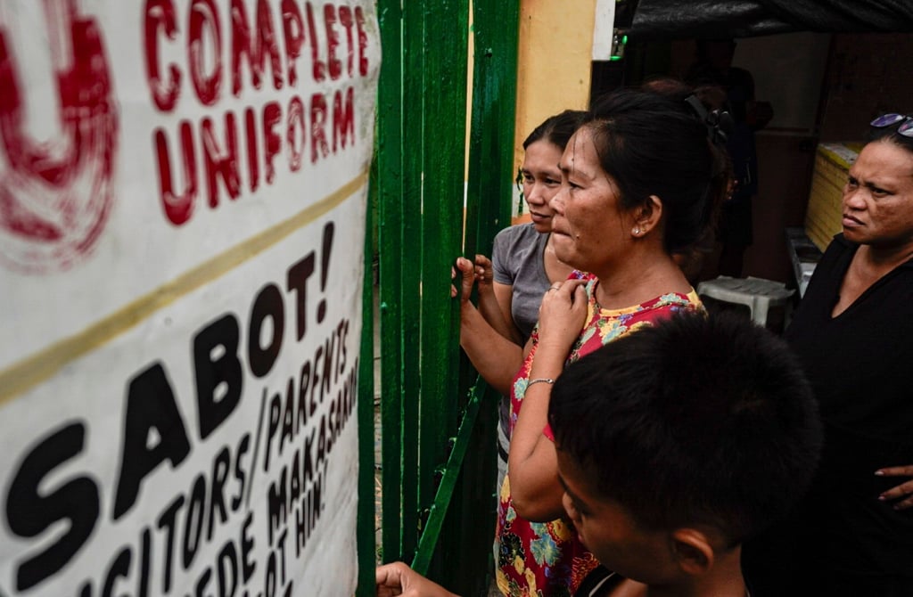 People look through the gates of San Jose National High School in Tacloban City on Monday. Photo: EPA People look through the gates of San Jose National High School in Tacloban City on Monday. Photo: EPA