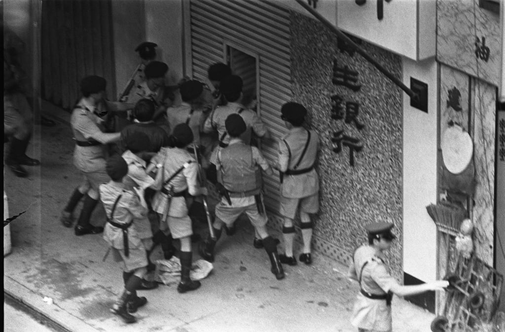 During an attempted robbery at Po Sang Bank on Shanghai Street, in Kowloon, heavily armed blue berets wearing bulletproof vests swarm through the narrow metal shutter door into the bank after the robber was pinned down by hostages. Photo: SCMP Archives
