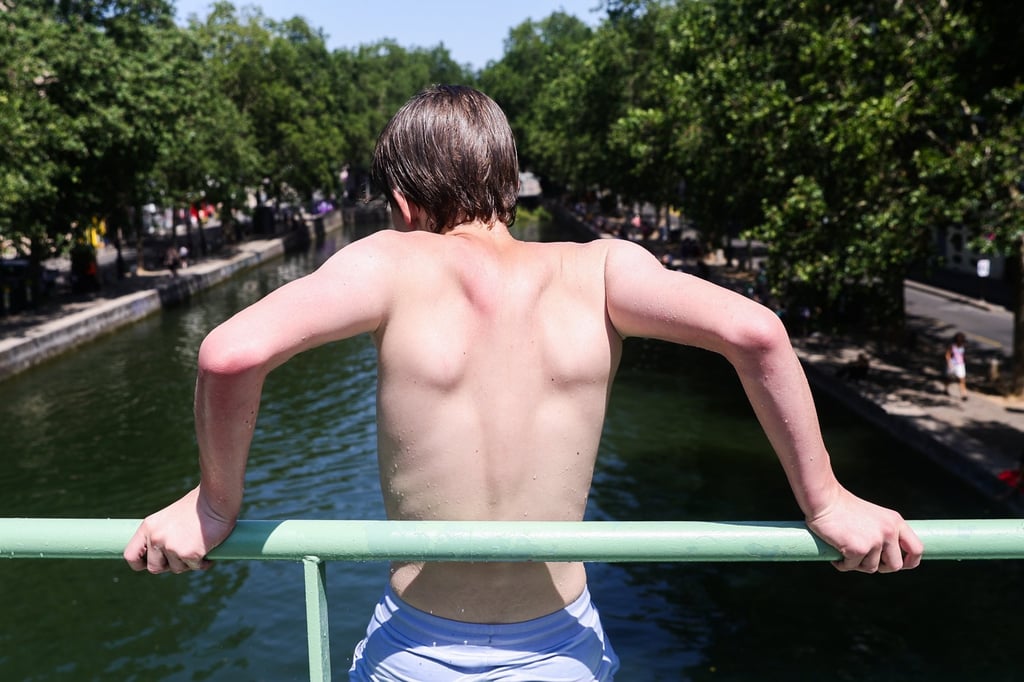 A boy prepares to jump into the water from a bridge in Paris, France, on Wednesday. Dozens of people have died across the country from drowning trying to escape the heat. Photo: EPA A boy prepares to jump into the water from a bridge in Paris, France, on Wednesday. Dozens of people have died across the country from drowning trying to escape the heat. Photo: EPA