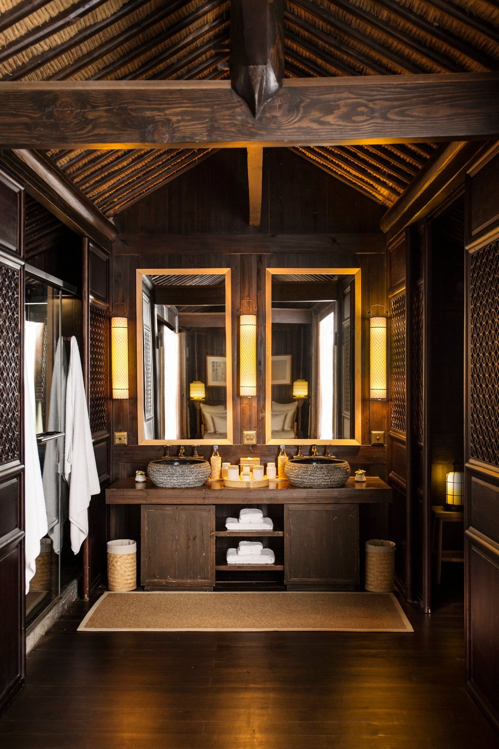 Dark timber, stone sinks and a thatched ceiling define the bathroom of a Village Room at Amanfayun. Photo: Handout