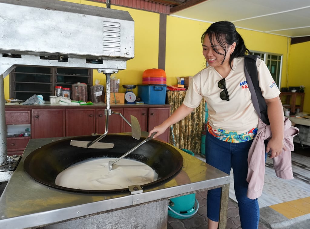 A tourist tries her hand at making coconut jelly during Eid al-Adha cultural activities organised by local tourism groups in Johor, Malaysia, on May 29. Photo: Xinhua
