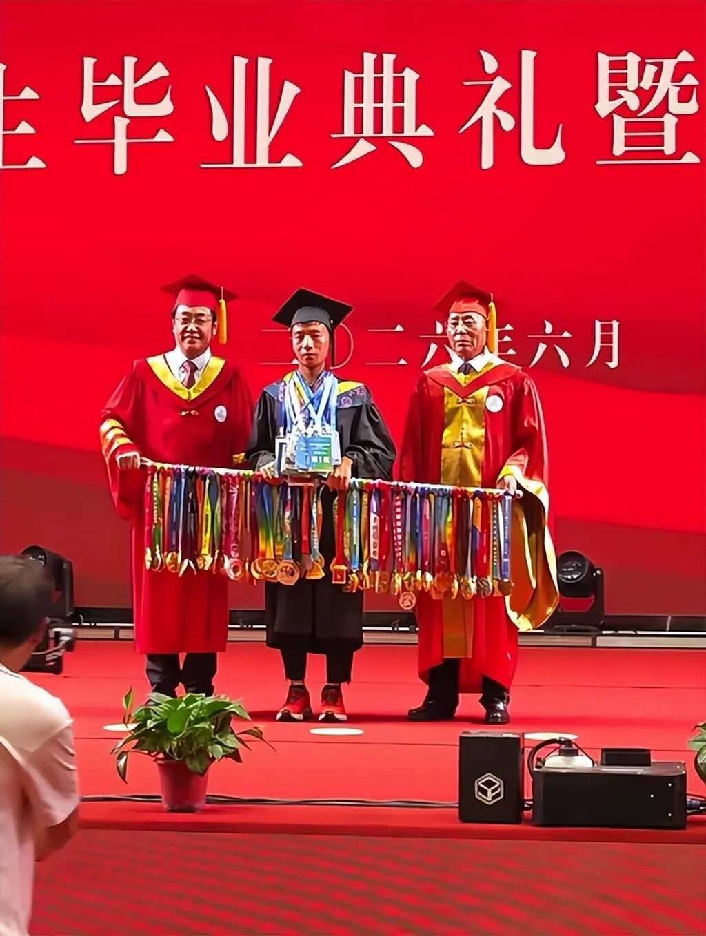 Upon receiving his degree, Jin stepped off the stage to grab a shoulder pole hung with dozens of medals, carrying it back up for an official graduation photo with university leaders. Photo: Handout Upon receiving his degree, Jin stepped off the stage to grab a shoulder pole hung with dozens of medals, carrying it back up for an official graduation photo with university leaders. Photo: Handout