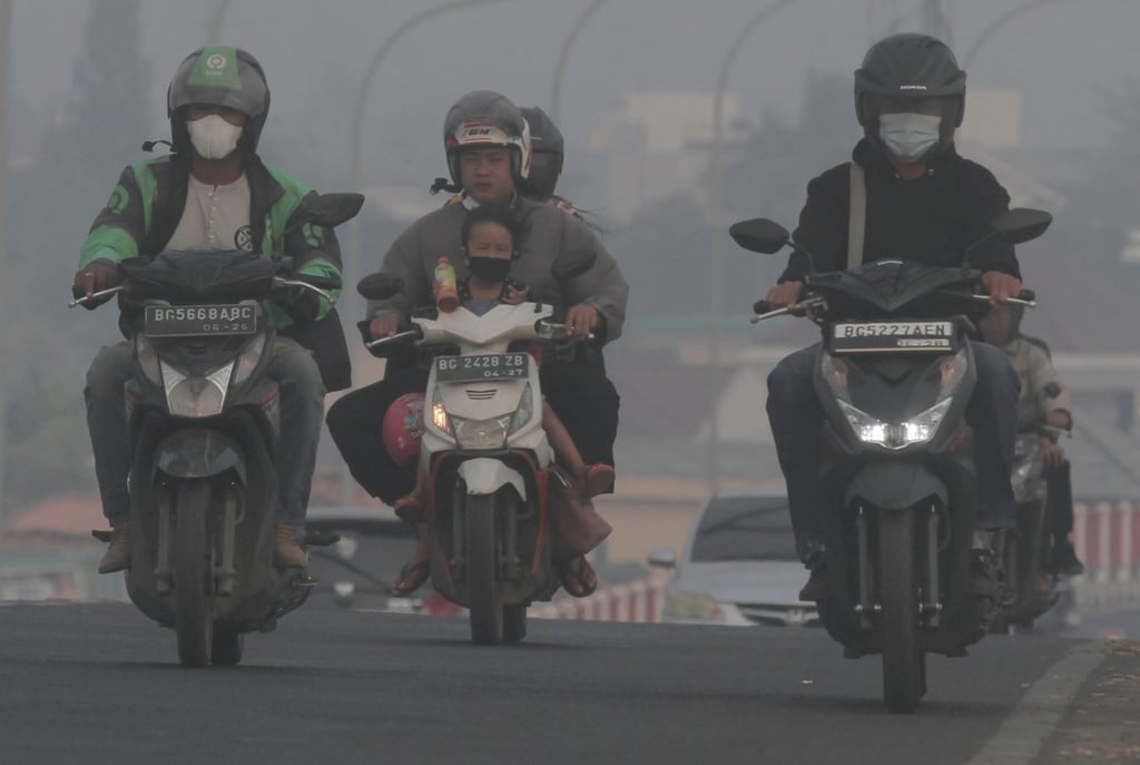Riders wear masks as they pass through the haze from forest fires in Palembang, South Sumatra, in October 2023. Photo: AP Riders wear masks as they pass through the haze from forest fires in Palembang, South Sumatra, in October 2023. Photo: AP