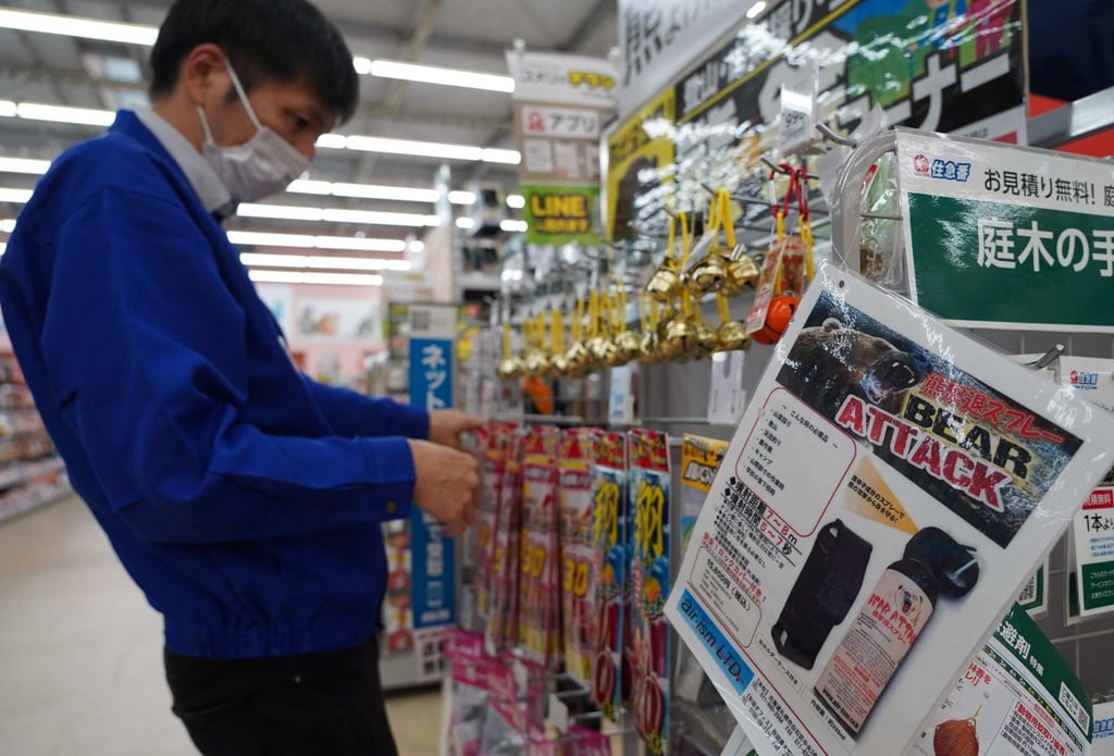 A staff member sorts bells next to an advertisement for bear spray at a store in Hanamaki, Iwate prefecture, in October 2025. Photo: AFP