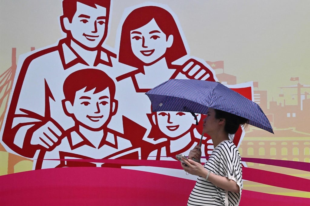 A pregnant woman holding an umbrella walks past a billboard in Hanoi showing a happy family last month. Photo: AFP A pregnant woman holding an umbrella walks past a billboard in Hanoi showing a happy family last month. Photo: AFP