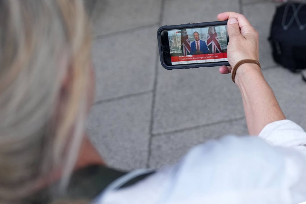Journalists in London watch on mobile phones as Reform UK Leader Nigel Farage makes a televised speech in which he resigned as MP for Clacton on Tuesday. Photo: AFP Journalists in London watch on mobile phones as Reform UK Leader Nigel Farage makes a televised speech in which he resigned as MP for Clacton on Tuesday. Photo: AFP